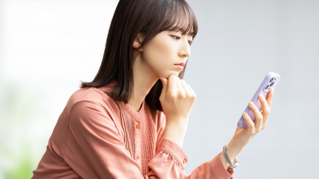 スマホを見て考える女性