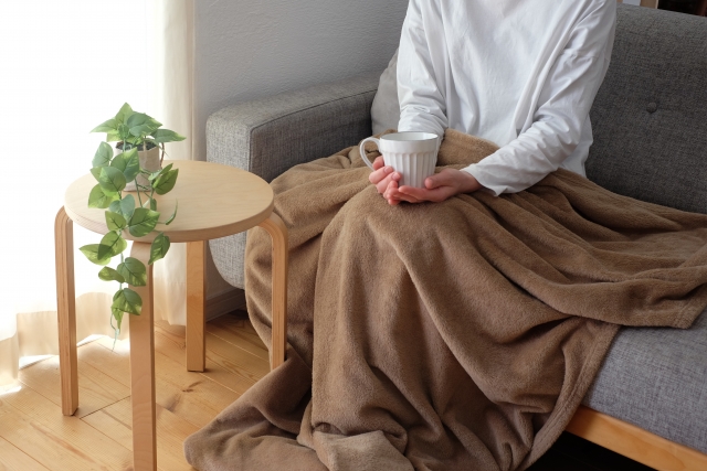 毛布を掛けながらくつろぐ女性