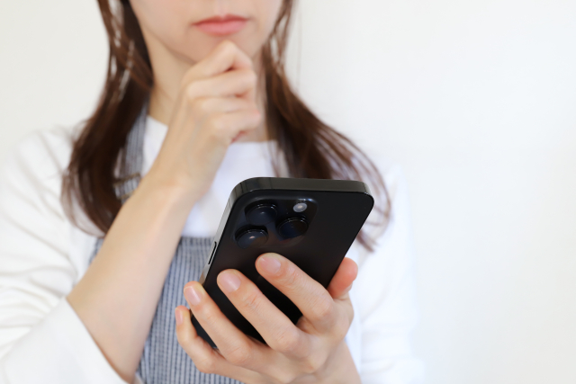 スマホを見て悩む女性