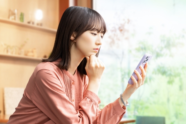 スマホを見ながら考える女性