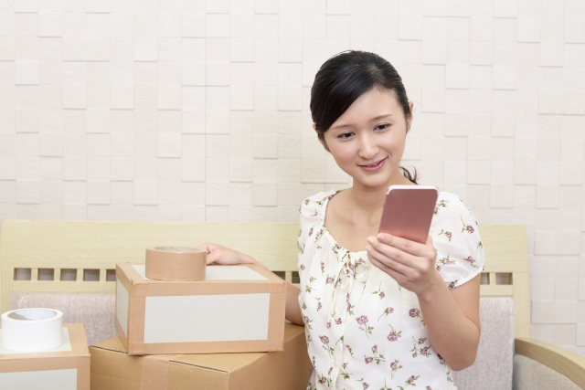 荷造りをしてスマートフォンを持つ女性