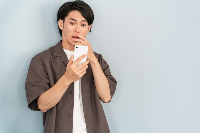 スマホ見て驚く男性