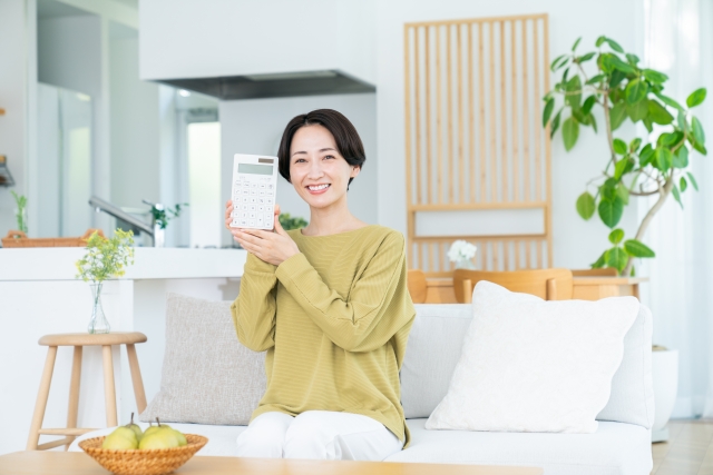 リビングで電卓を持つ女性