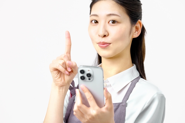 スマホを持ち指さしポーズする女性